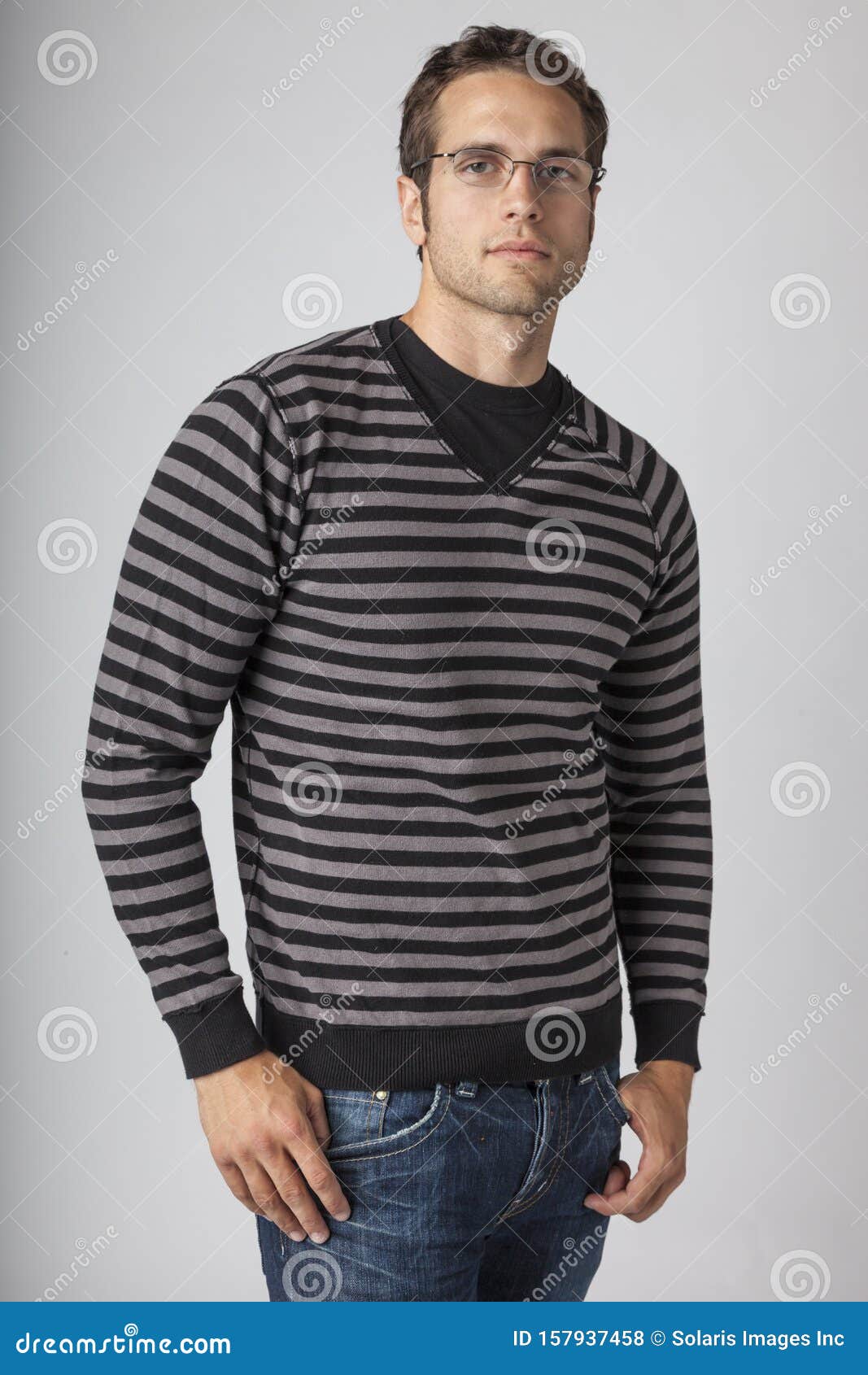 young man wearing striped sweater, denim jeans and eyeglasses. men`s casual fall clothing apparel fashions styles.