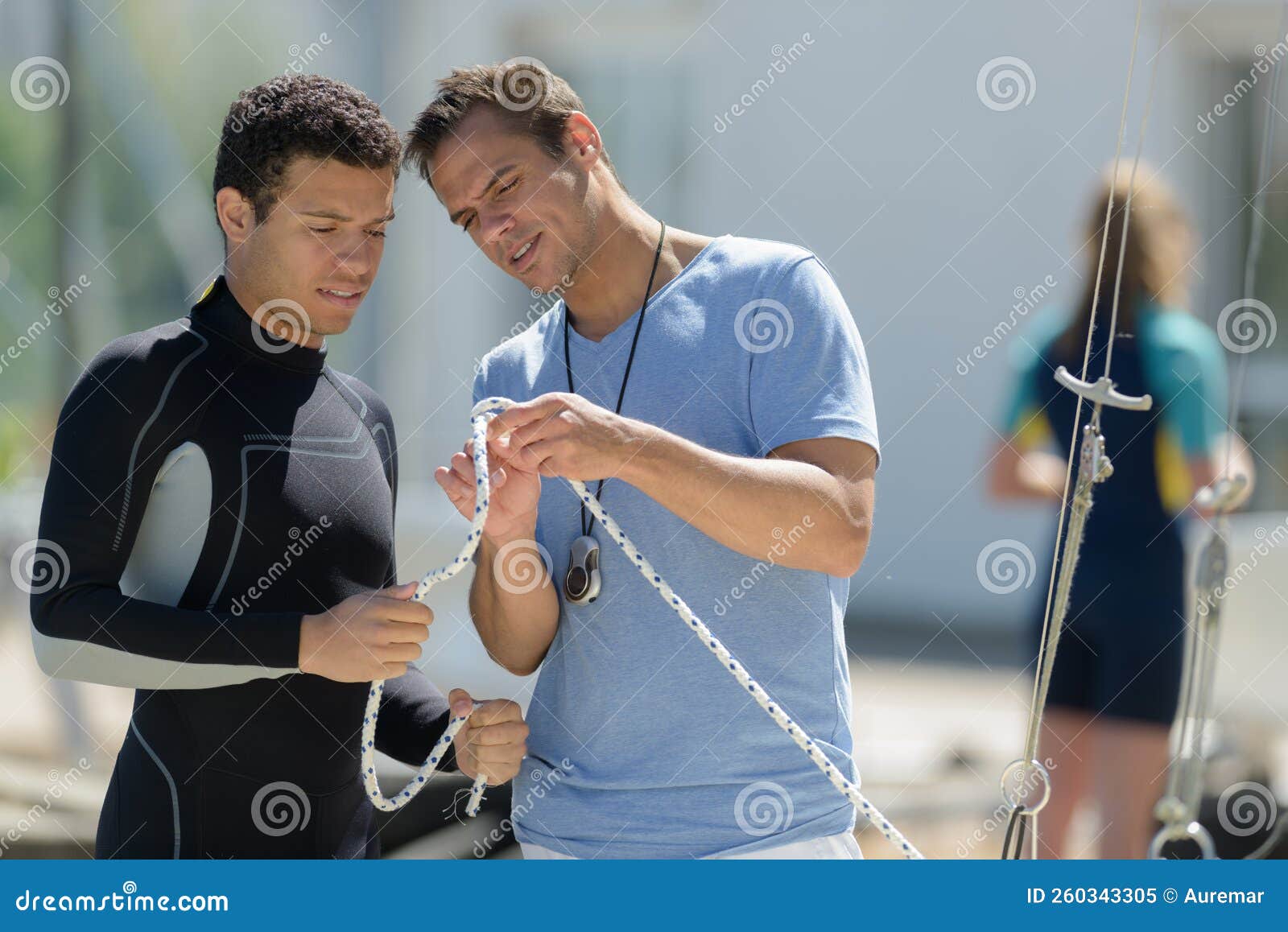 young man in wetsuit learning how to knot rope