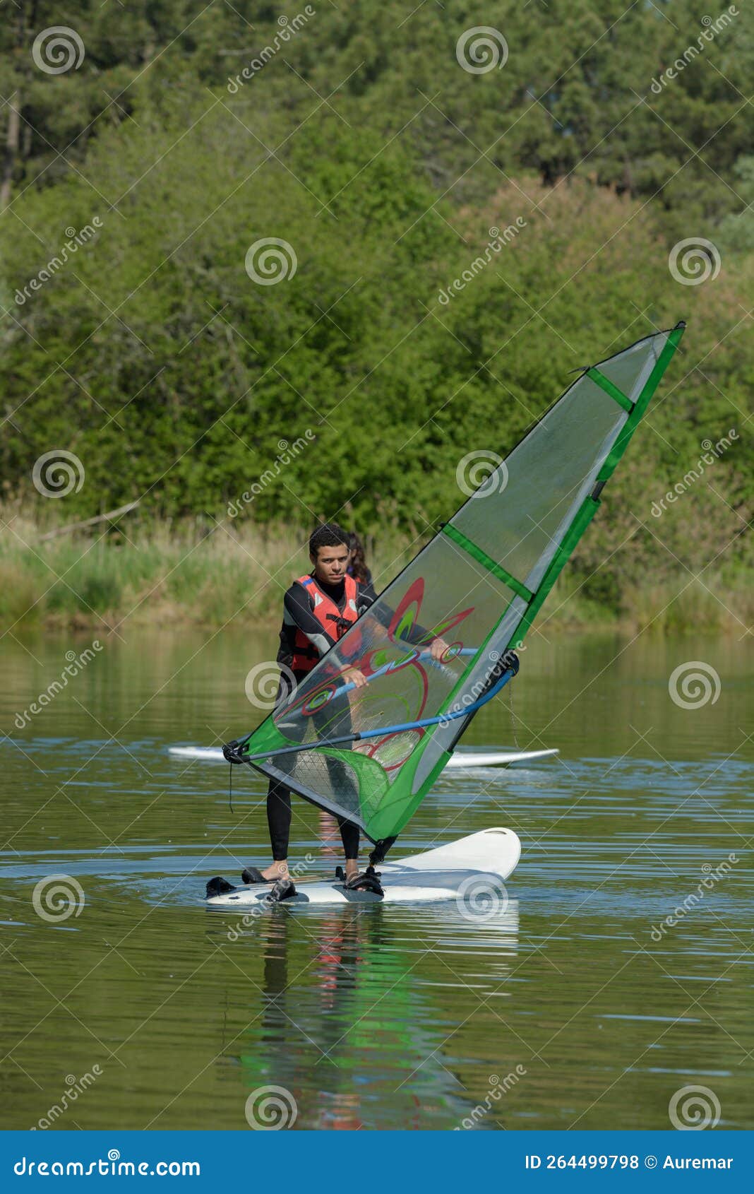 young man windsurfing on lake