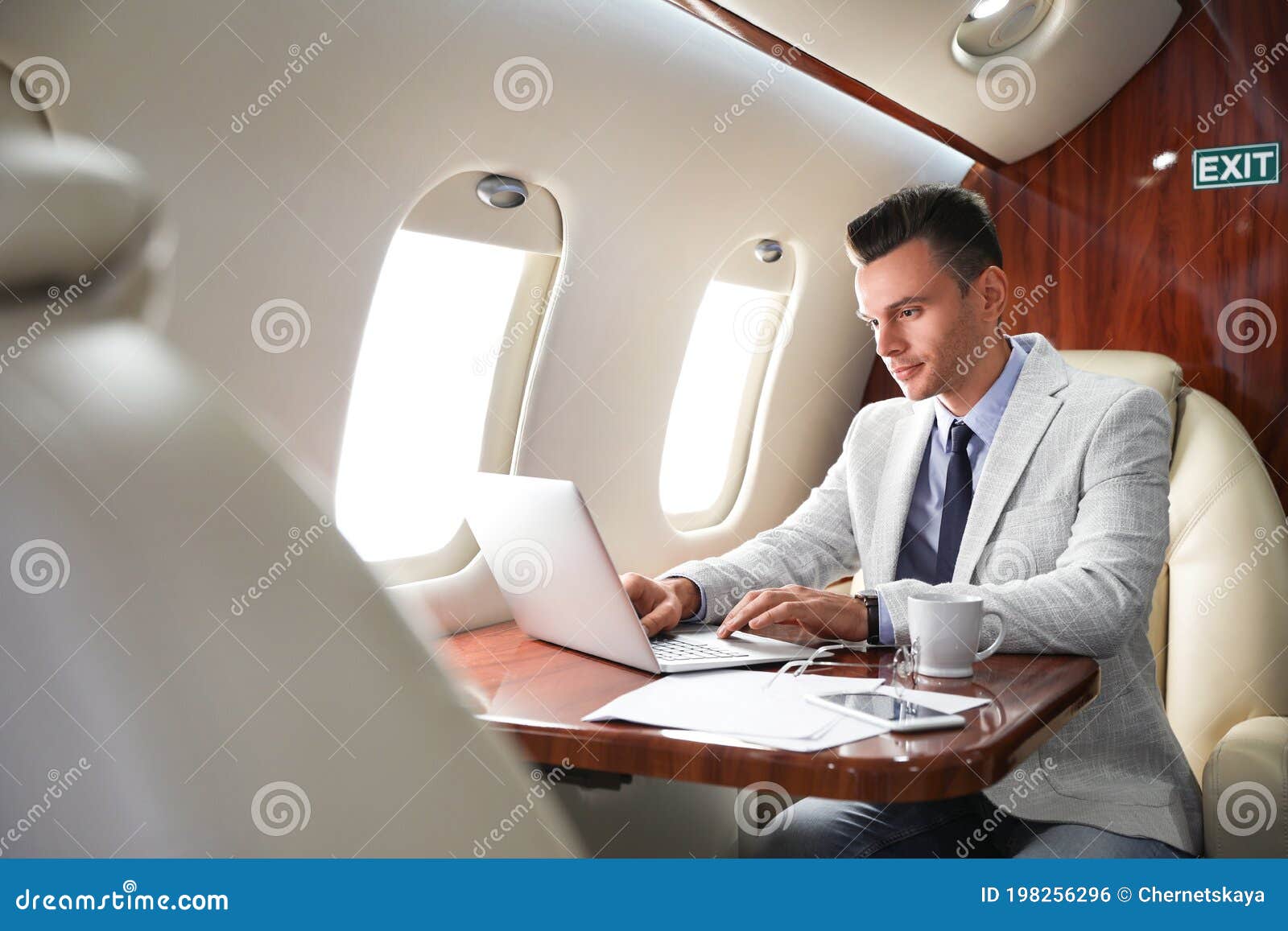 Young Man Working with Laptop on Plane. Comfortable Flight Stock Photo