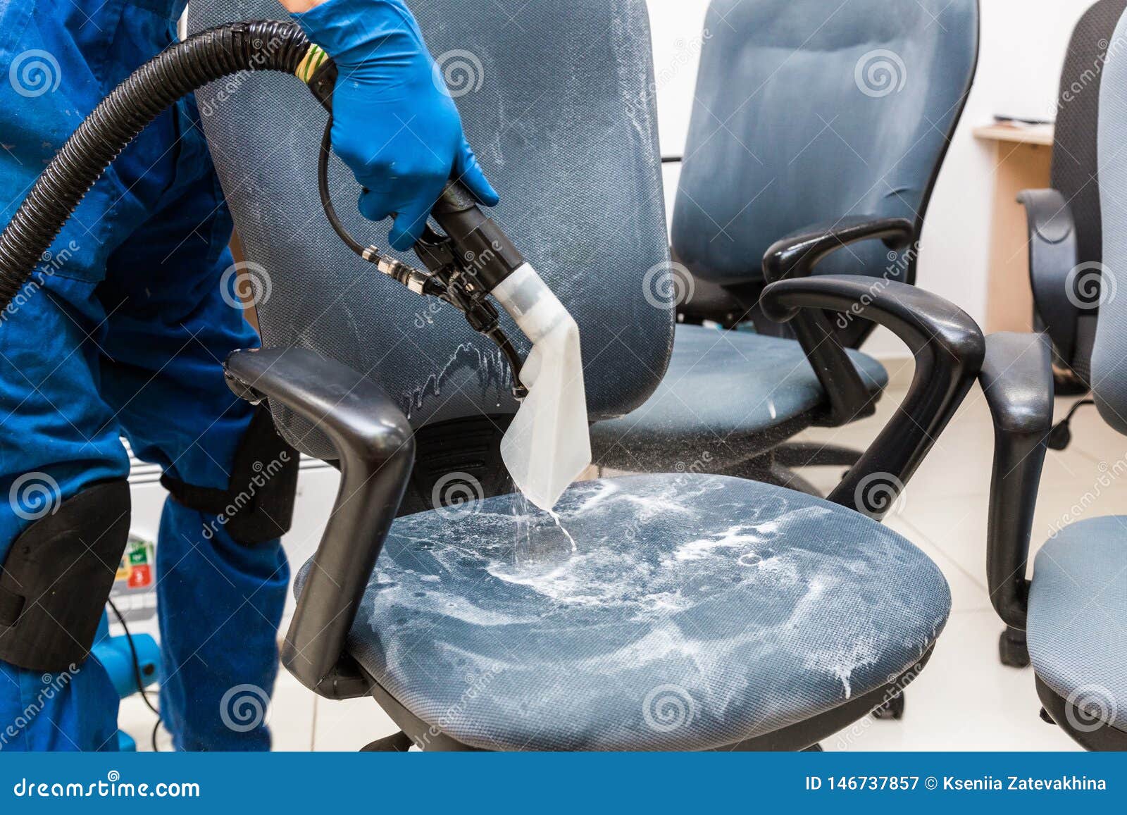 Young Man In Workwear And Rubber Gloves Cleans The Office Chair