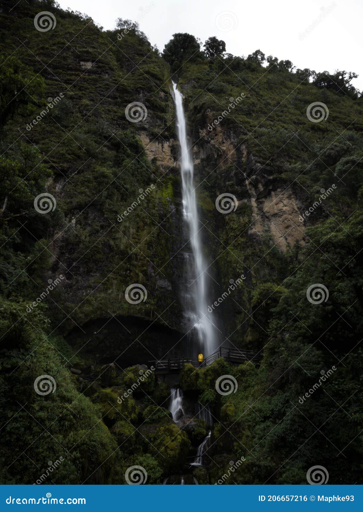 young man in yellow jacket in front of el chorro de giron waterfall cascade cataract near cuenca azuay ecuador