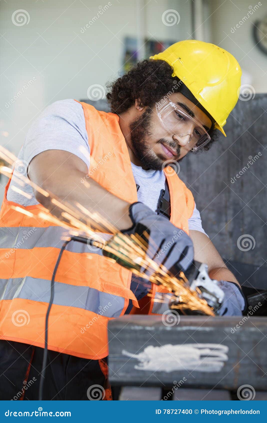 young manual worker in protective workwear grinding metal in industry