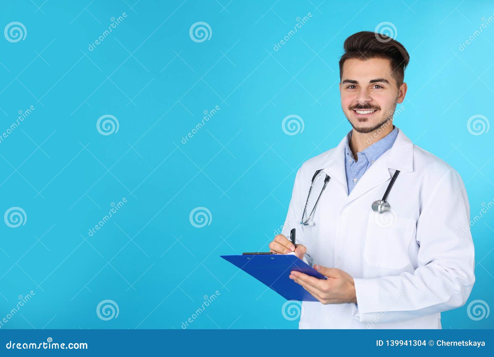 Young Medical Student with Clipboard on Color Background. Stock Photo