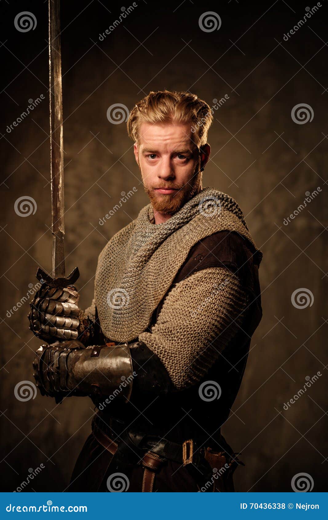 young medieval knight posing on dark background.