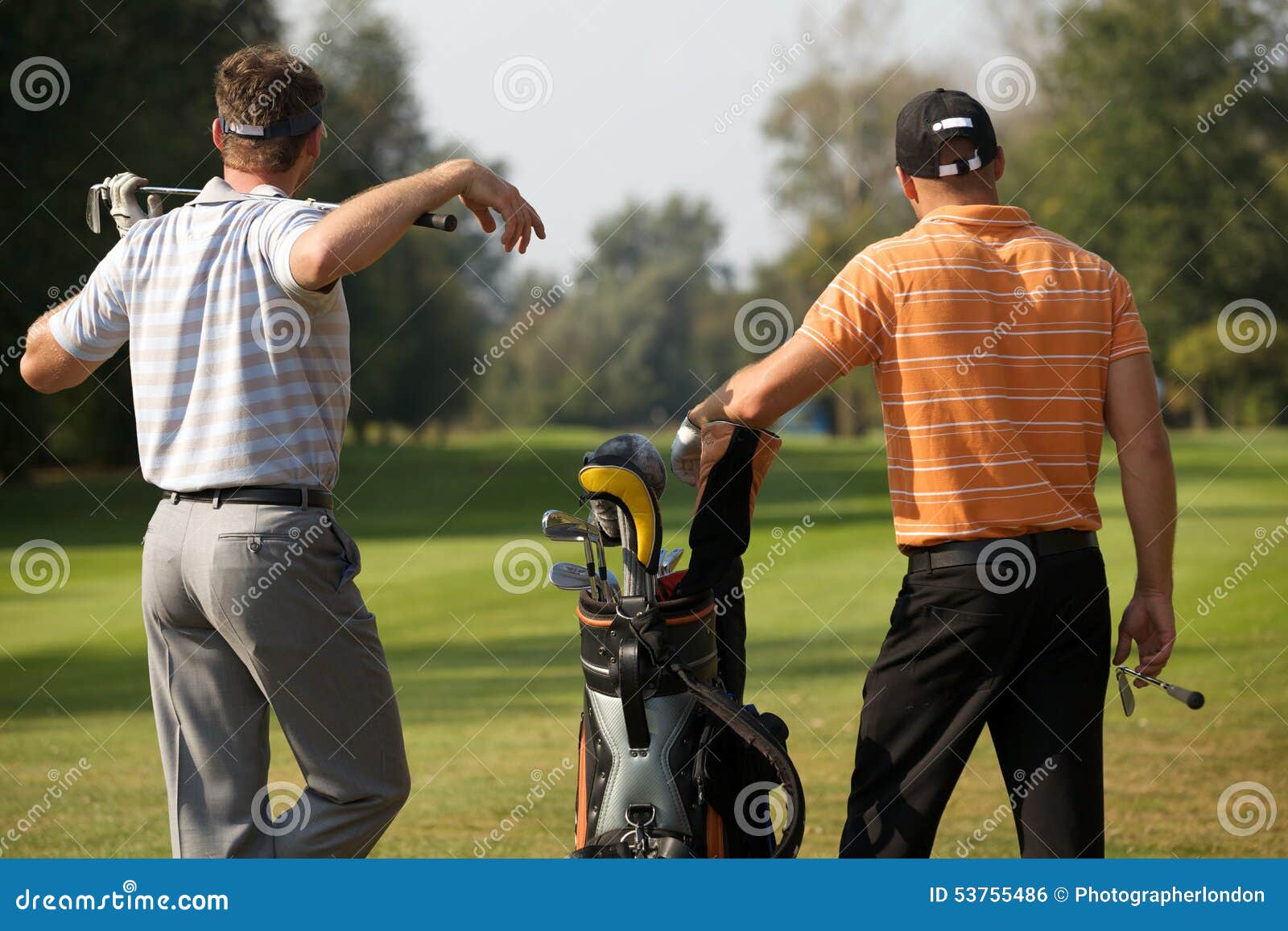 Young Men Standing in Golf Course by Golf Bag Full of Sticks Stock