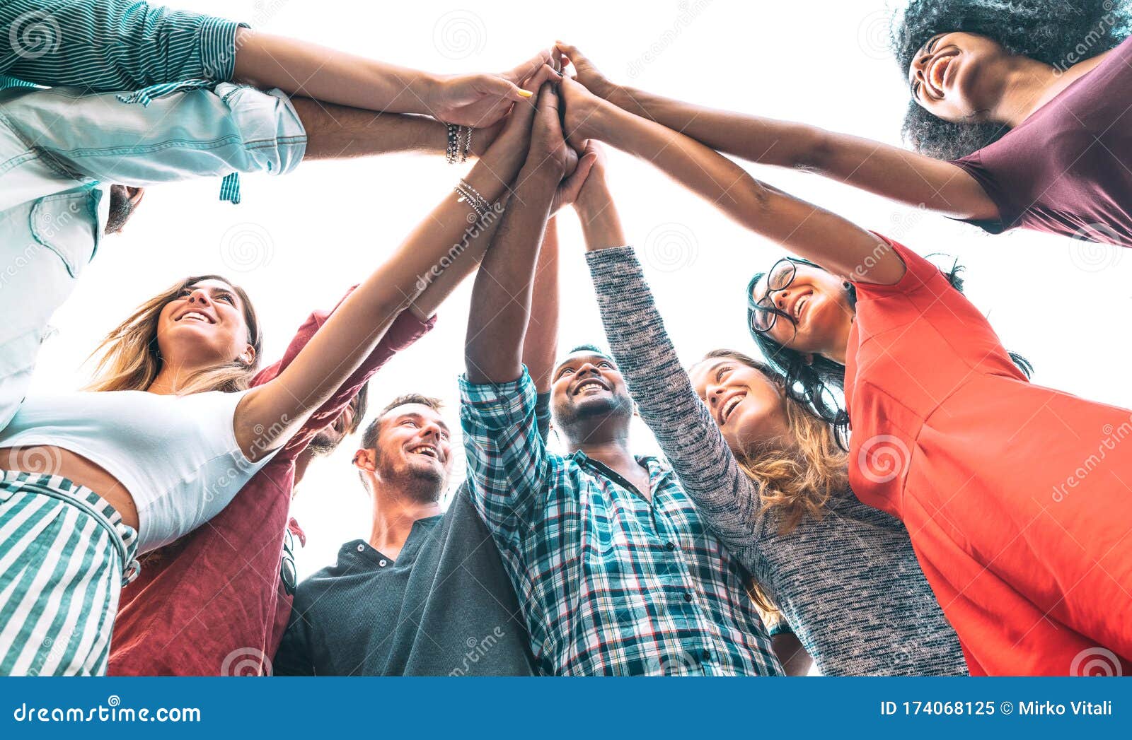 young millenial friends stacking hand on high five move - multiracial culture and unity with students having fun together