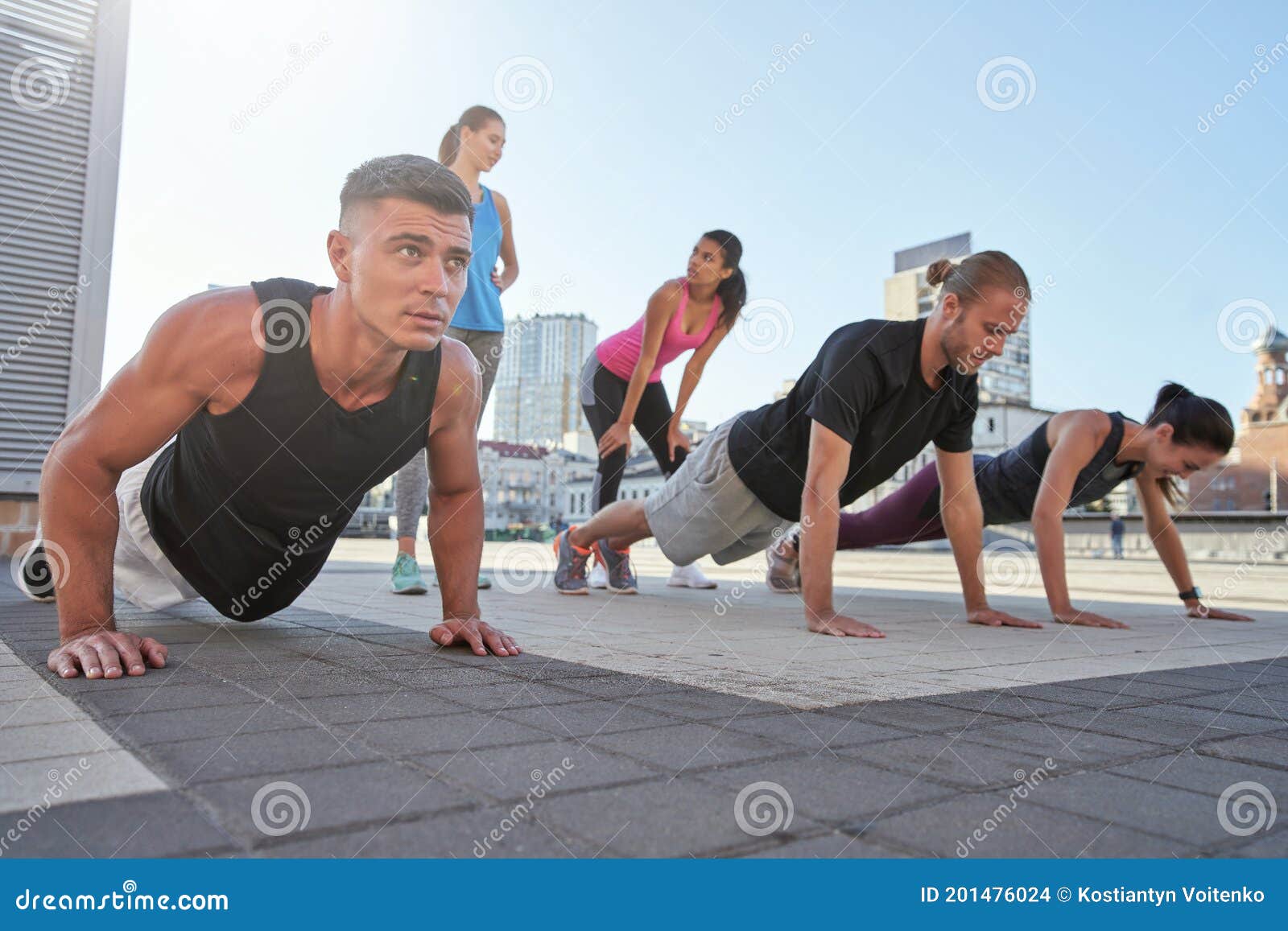 Young Mixed Race Athletes Doing Push Ups on City Square Stock Photo