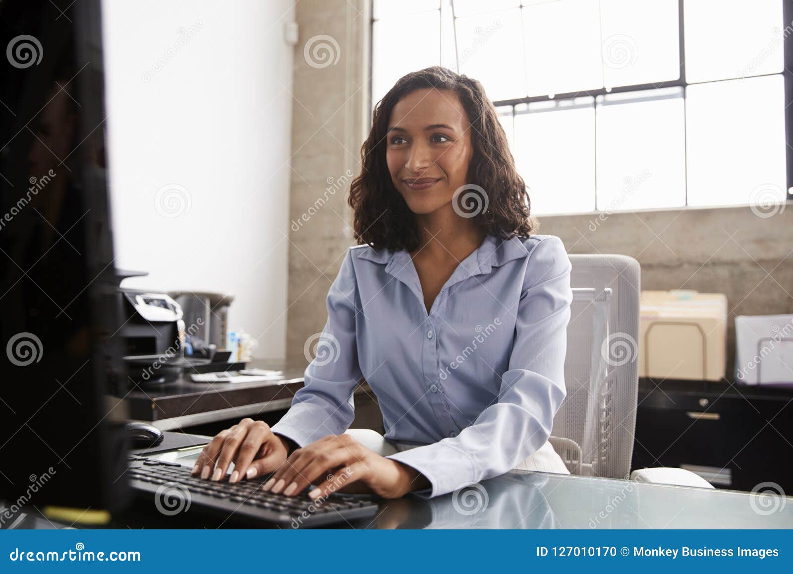 mixed race young woman typing on computer keyboard at table with