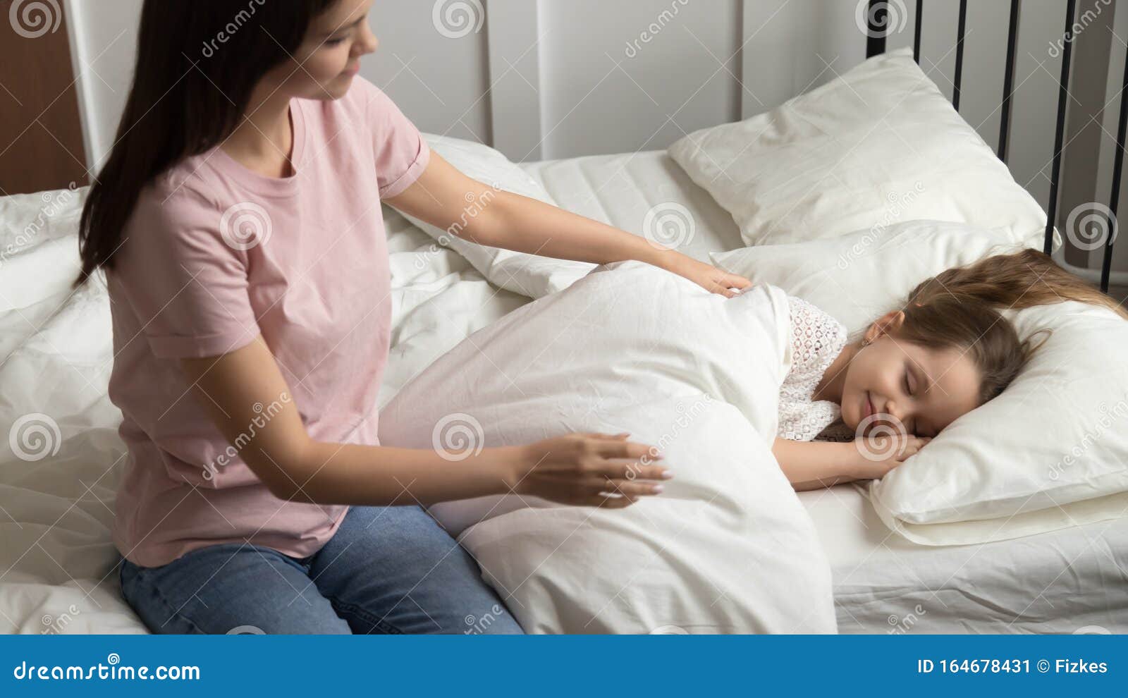 young mom caress little daughter put her to sleep