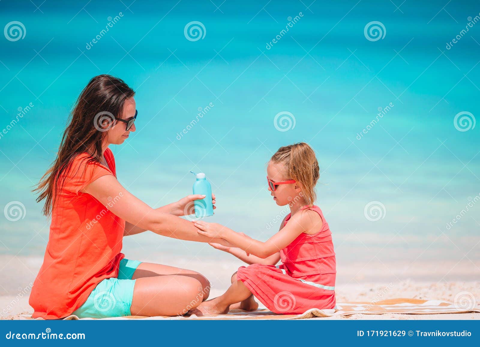 Young Mother Applying Sun Cream To Daughter Nose On The Beach Sun