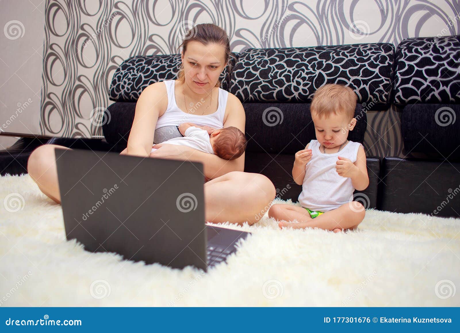 A Young Mother is Breastfeeding a Baby and is Simultaneously Working on