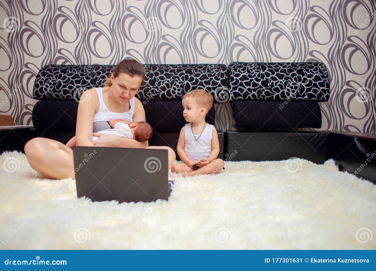 A Young Mother is Breastfeeding a Baby and is Simultaneously Working on