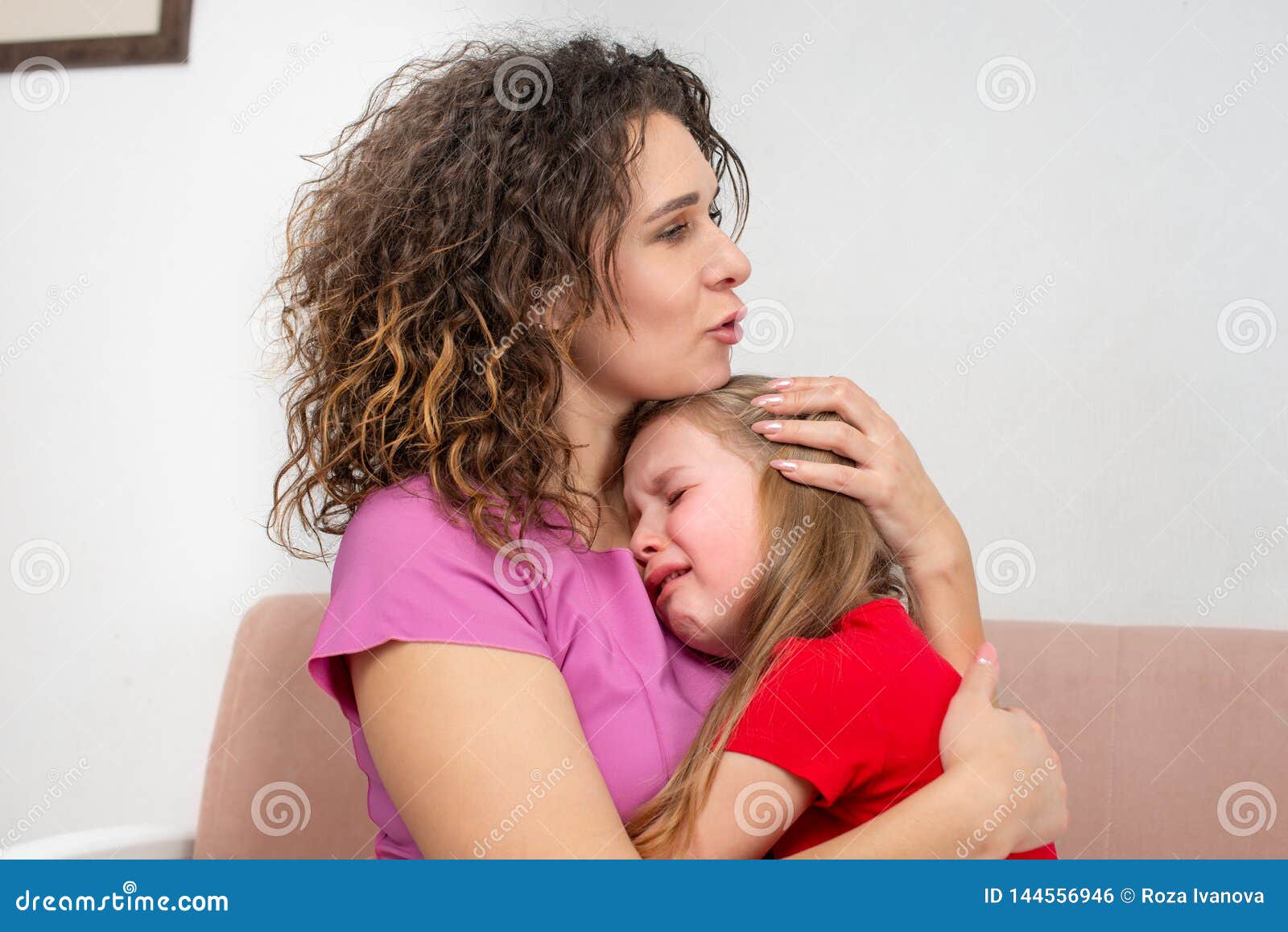 A Young Mother Calms Her Daughter. the Girl is Crying and Her ...