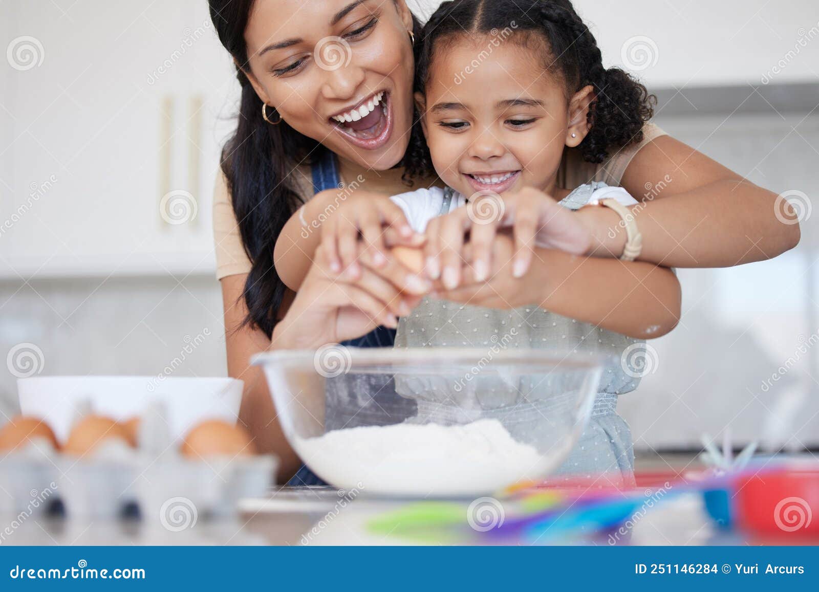 young mother enjoying baking, bonding with her little daughter in the kitchen at home. little latino girl smiling while