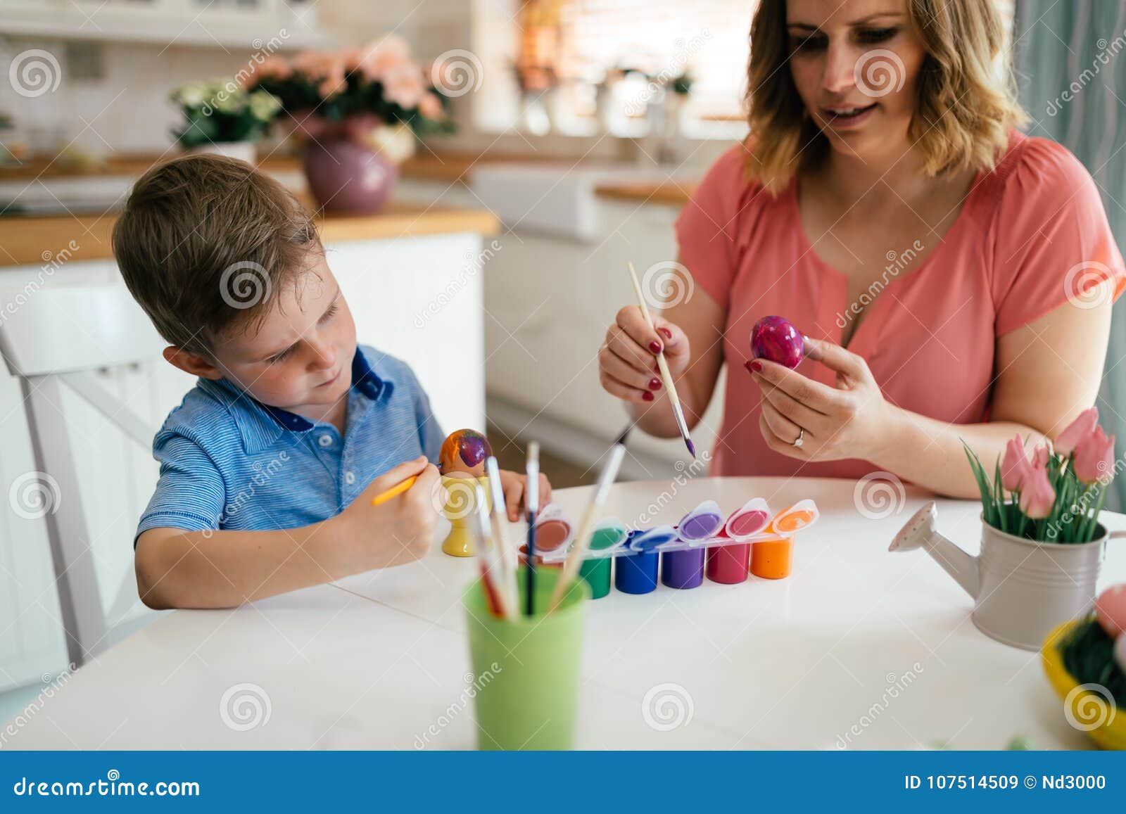 Young Mother And Her Son Having Fun While Painting Eggs For Easter