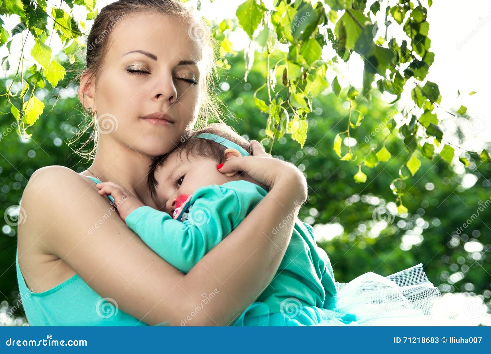 Young mother like. Мама обнимает ребенка на улице. Мама обнимает ребёнка на природе. Женщина в зеленом обнимает ребенка.