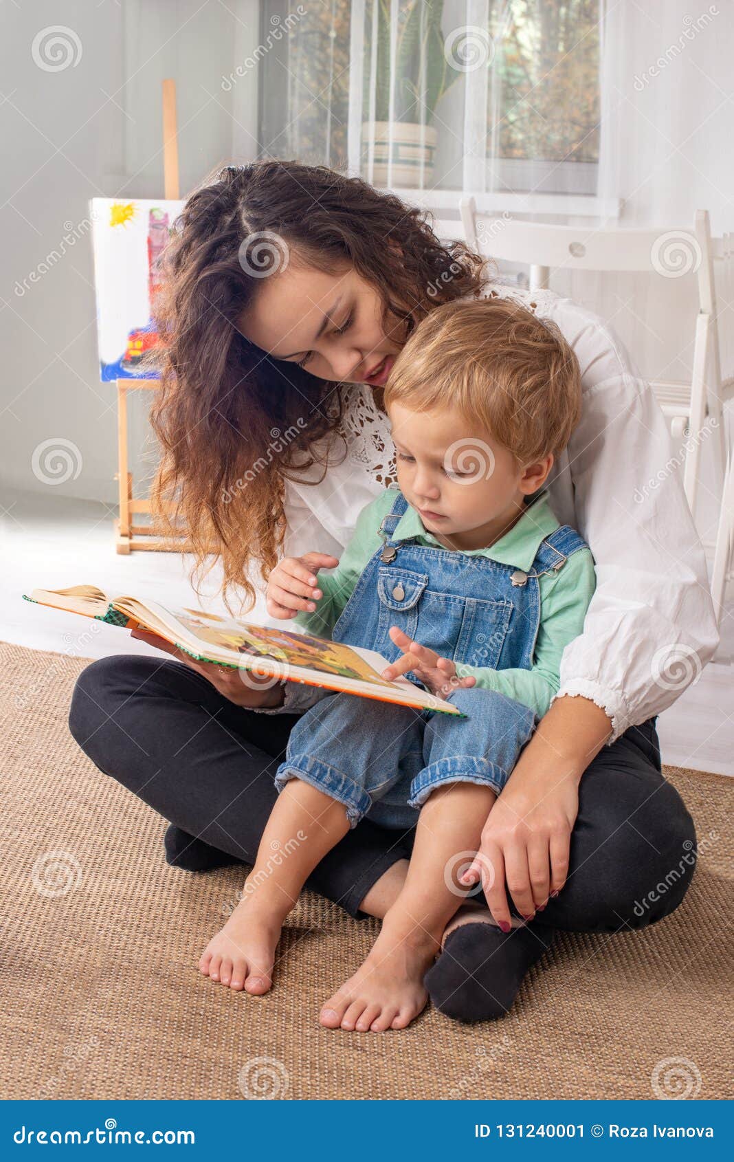 young mother or nanny with small child boy sit on the floor on a