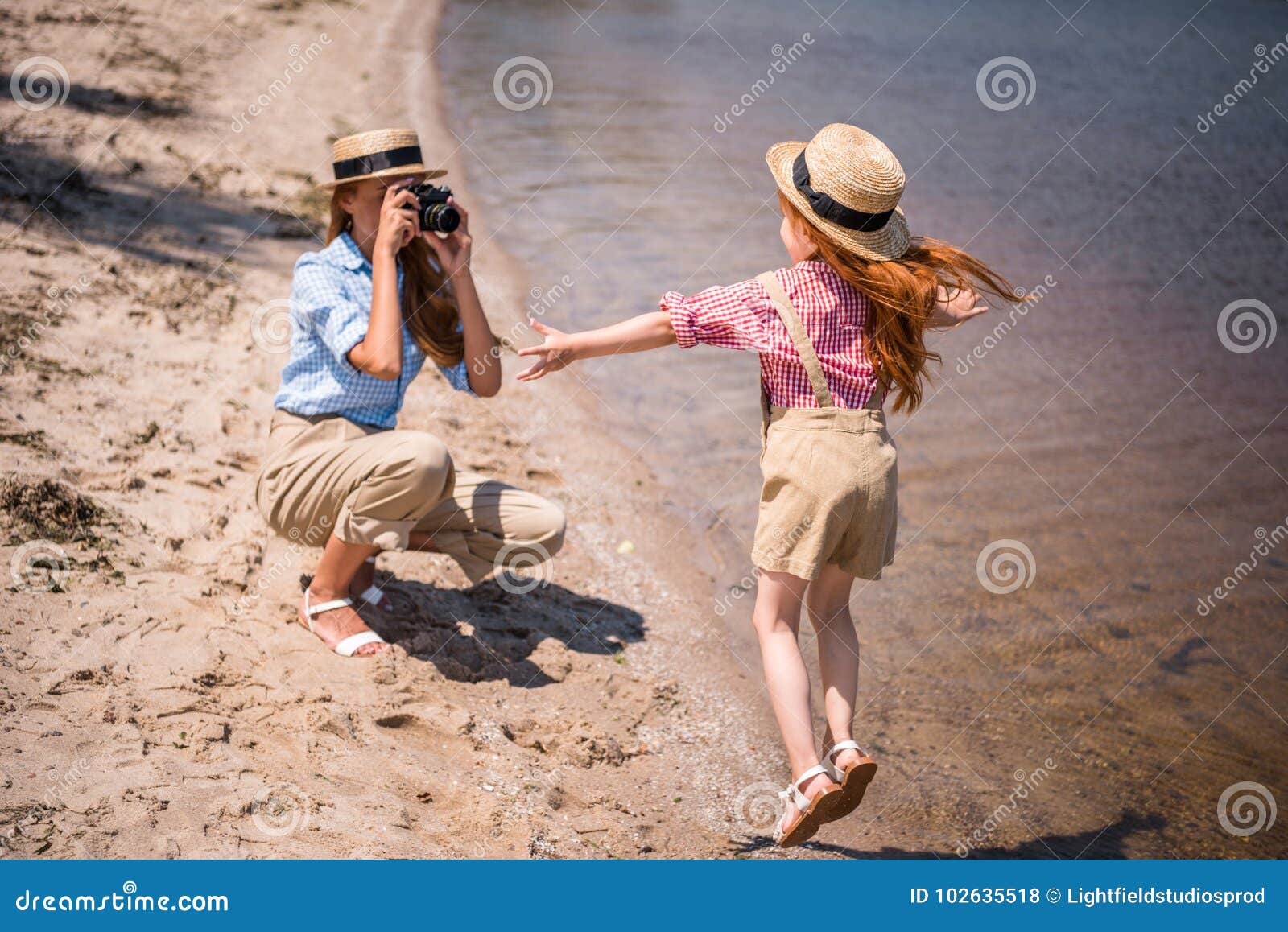Mother Photographing Daughter On Beach Stock Photo - Image of