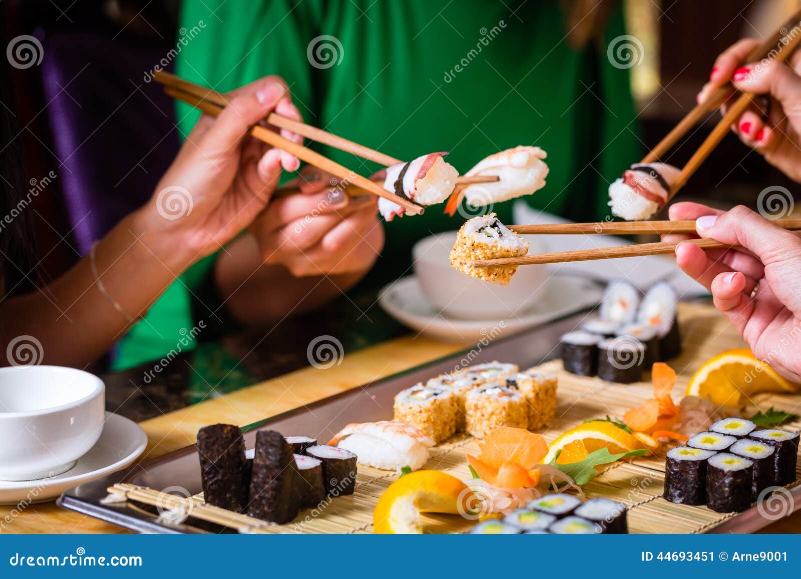 young people eating sushi in restaurant