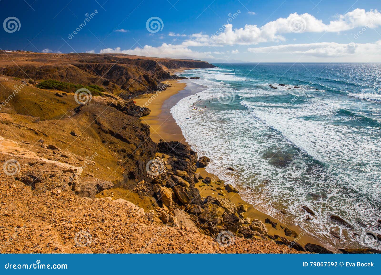 young people surfing on la pared beach with vulcanic mountains in the background on fuerteventura island, canary islands, spain