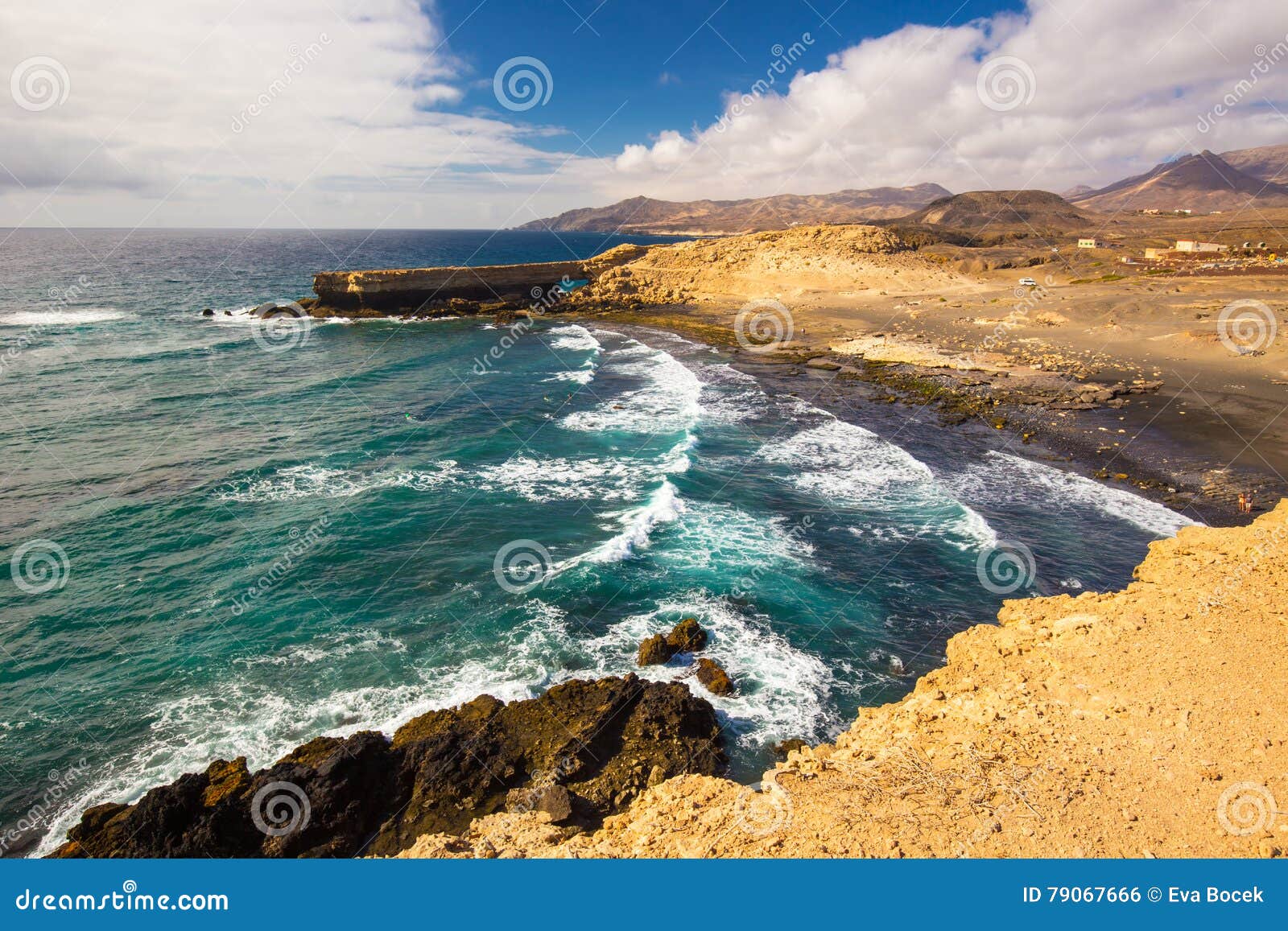 young people surfing on la pared beach with vulcanic mountains in the background on fuerteventura island, canary islands, spain