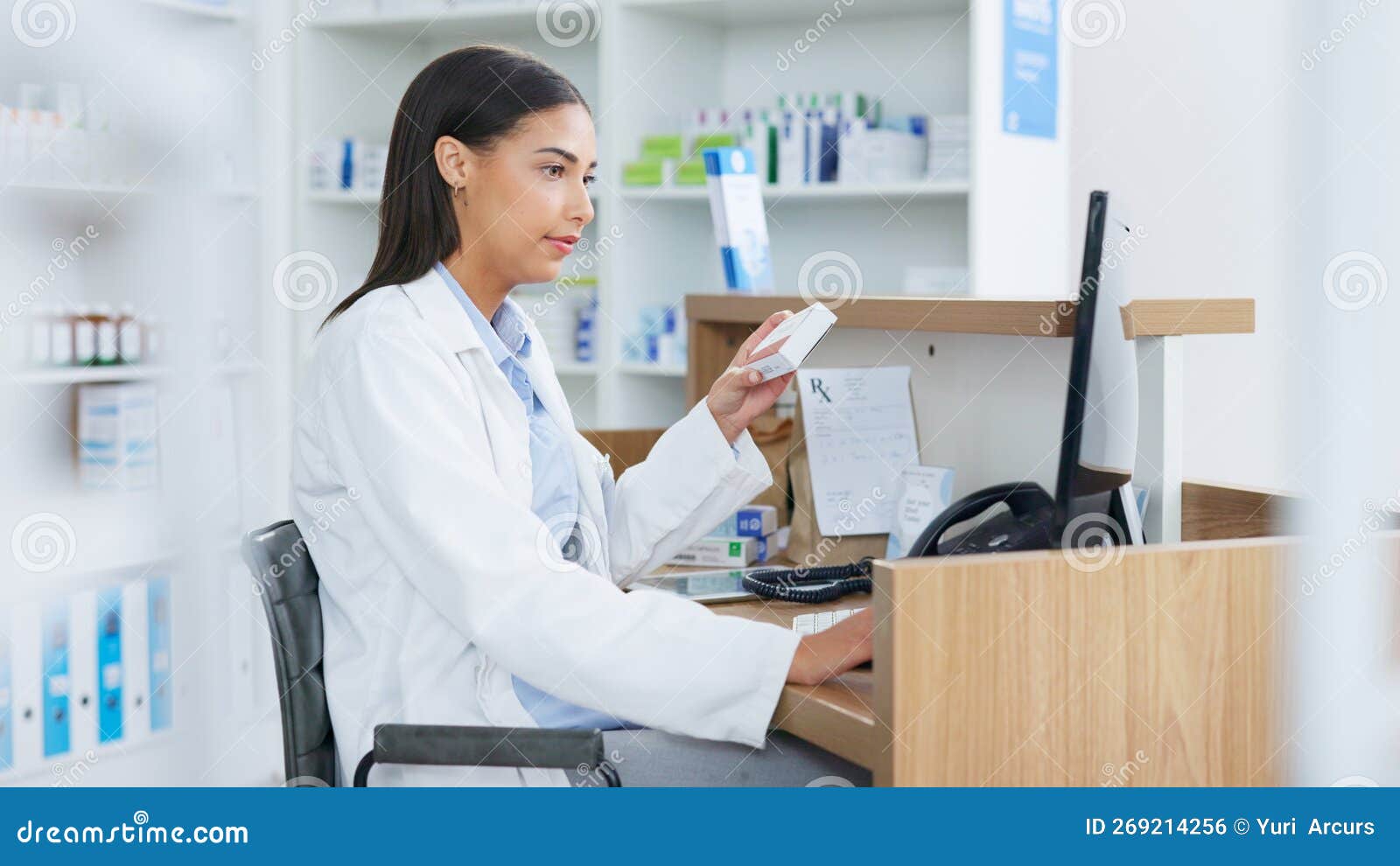 Young Pharmacist Working on Computer at a Pharmacy Counter. Woman Using