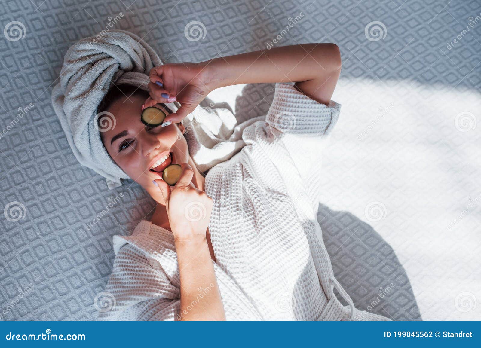 Young Positive Woman with Towel on Head Lying on the Bed with Cucumber ...