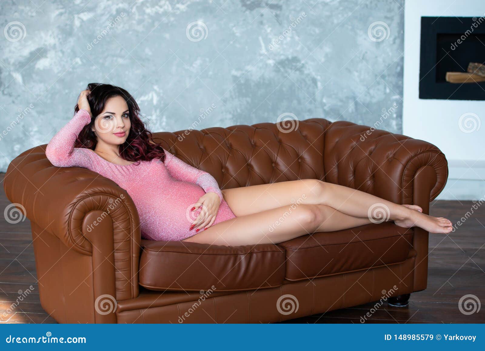 a young pregnant brunette woman on a sofa in the interior of the living room