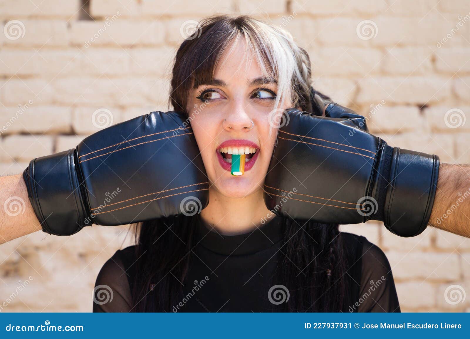 young and pretty girl with a punkish tendency. she is being hit on each side of her face with boxing gloves while holding a jelly