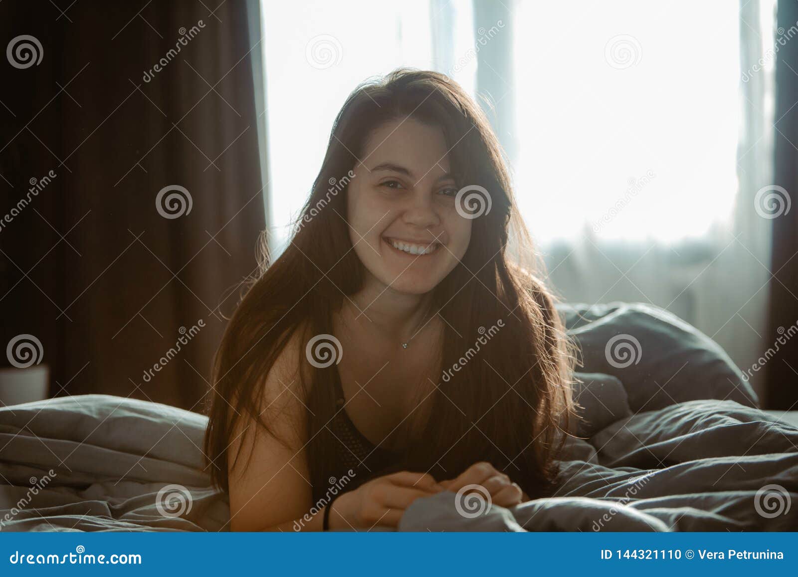 Young Pretty Woman in Black Bra Sitting on Bed. Morning Time Stock
