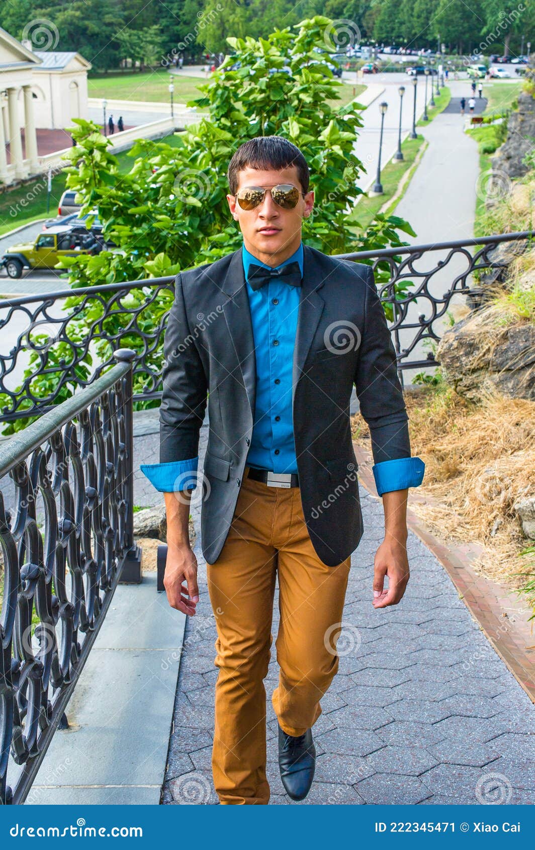 Man Waiting for You. Wearing a blue blazer, black pants,, short haircut, a  young black guy is standing against metal fences by a tennis court, staring  Stock Photo - Alamy