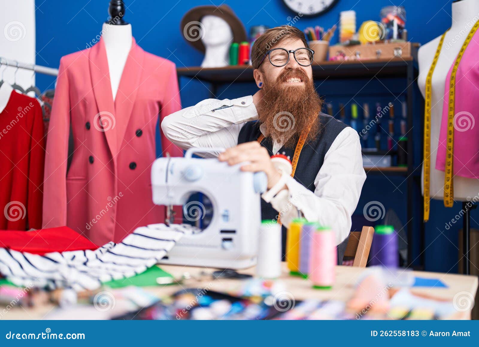 Young Redhead Man Tailor Stressed Using Sewing Machine at Clothing