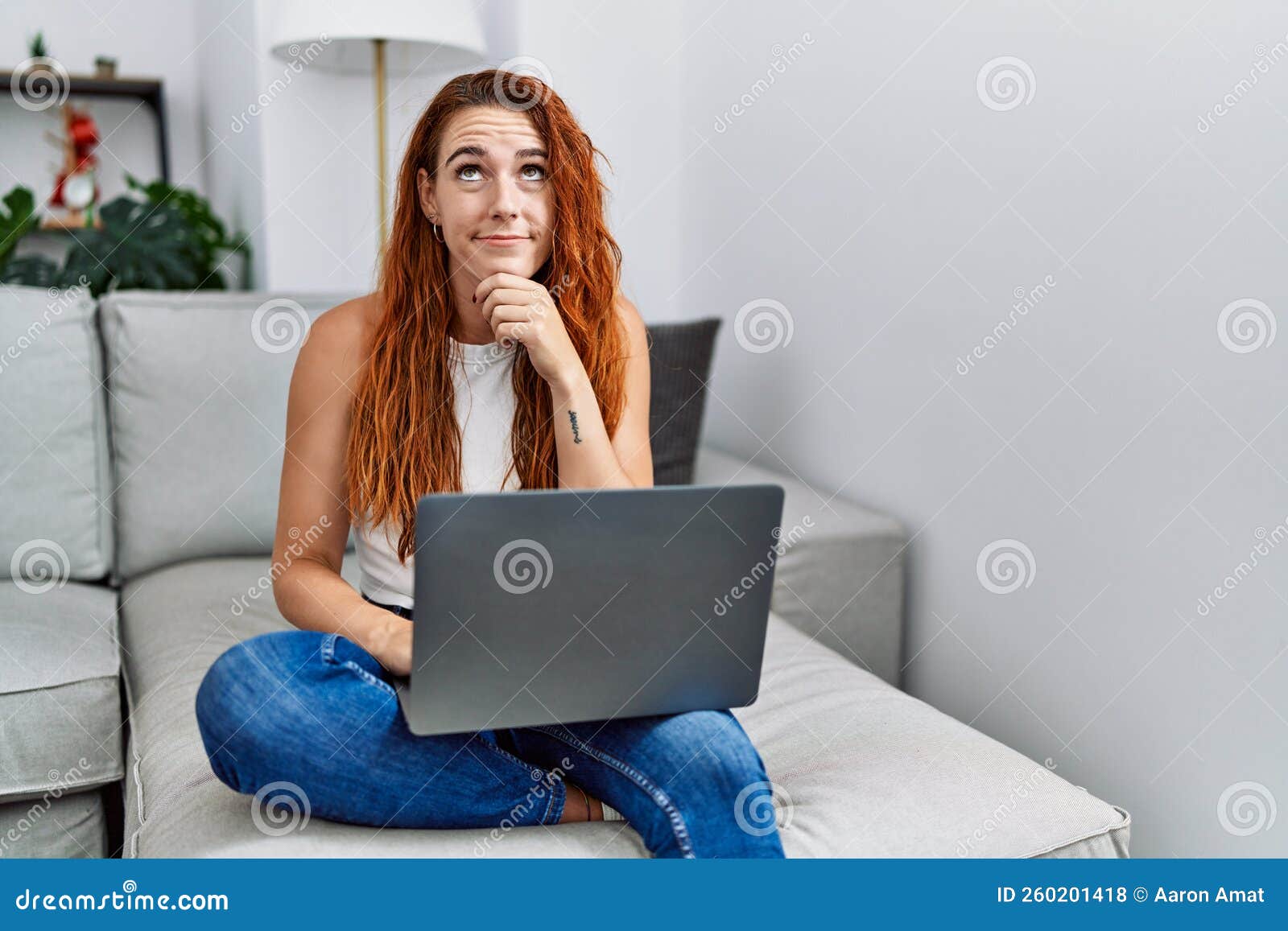 Young Redhead Woman Using Laptop at Home Serious Face Thinking about