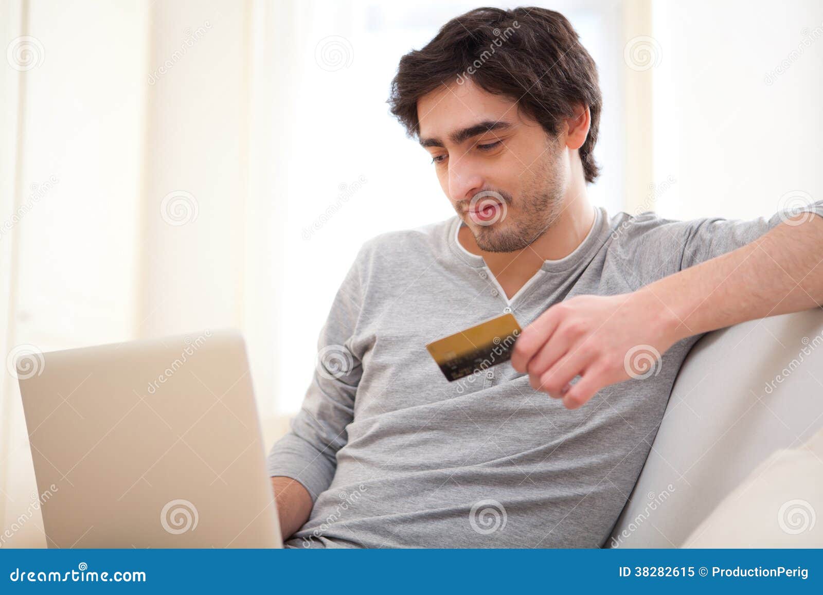 Young Relaxed Man Paying Online with Credit Card in Sofa Stock Image