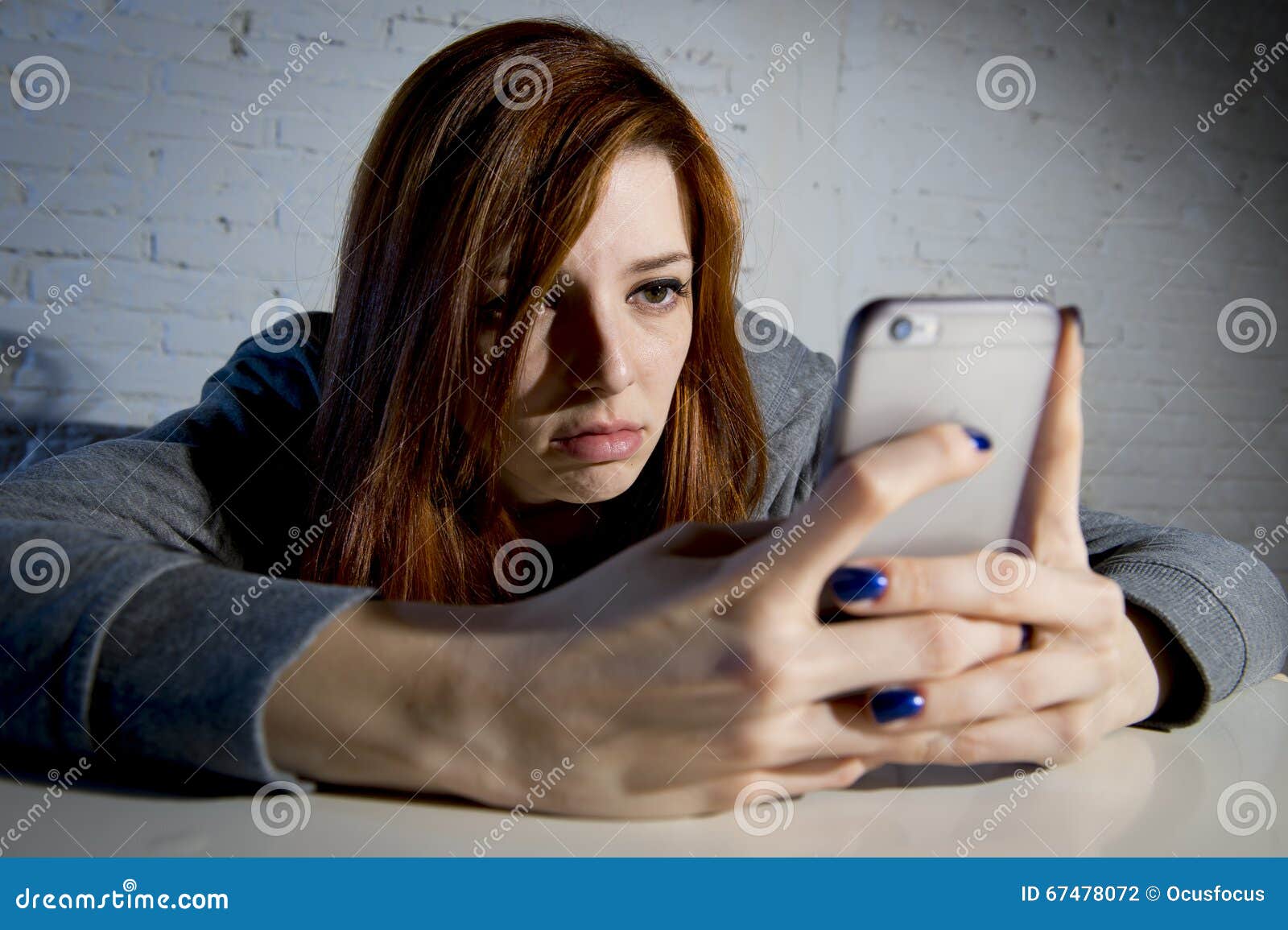 young sad vulnerable girl using mobile phone scared and desperate suffering online abuse cyberbullying