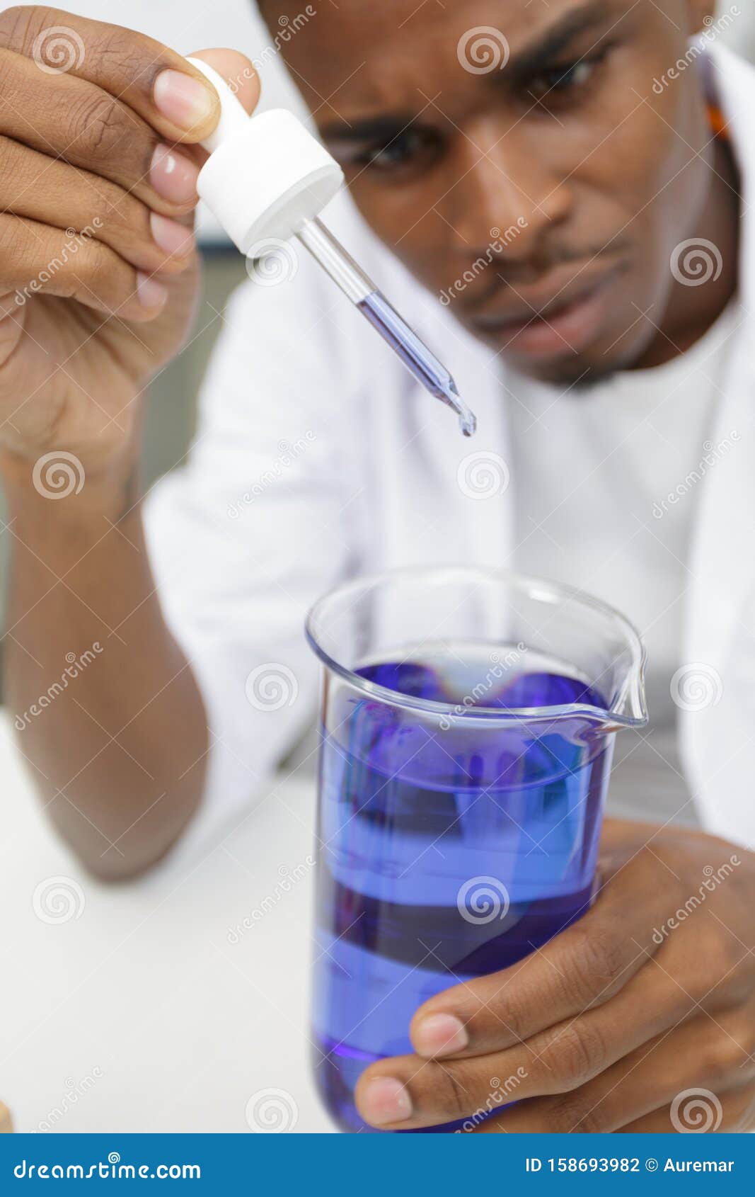 Young Scientist with Violet Solution in Pipette Dropper Stock Photo