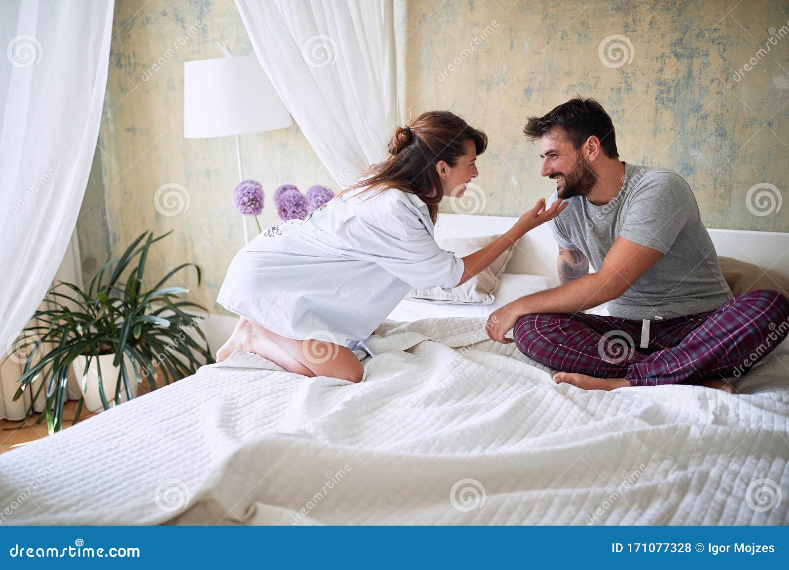 young sexy couple in underwear having a foreplay in bed in the morinig on valentines day. intimacy, passion, erotic concept
