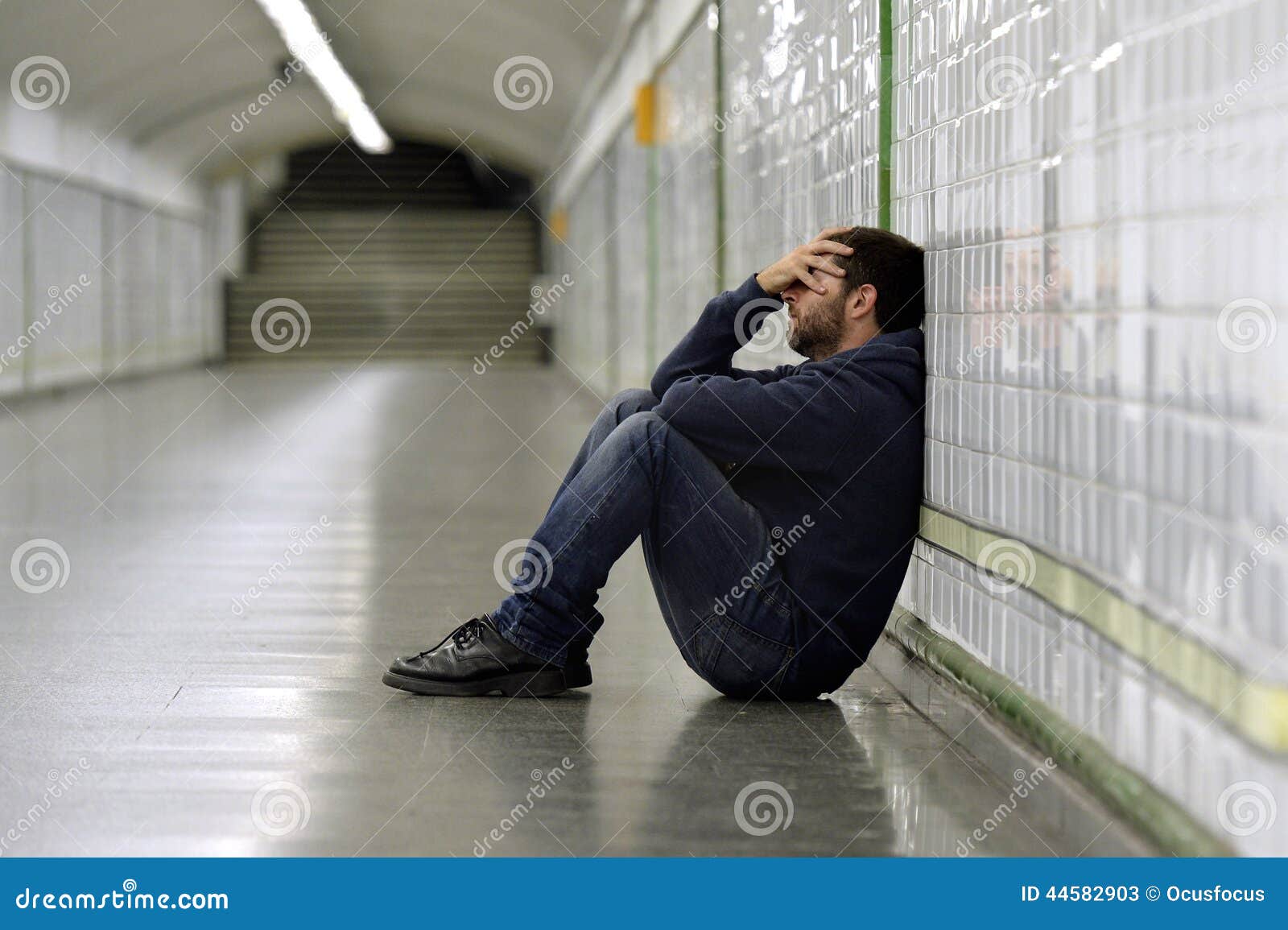 young sick man lost suffering depression sitting on ground street subway tunnel