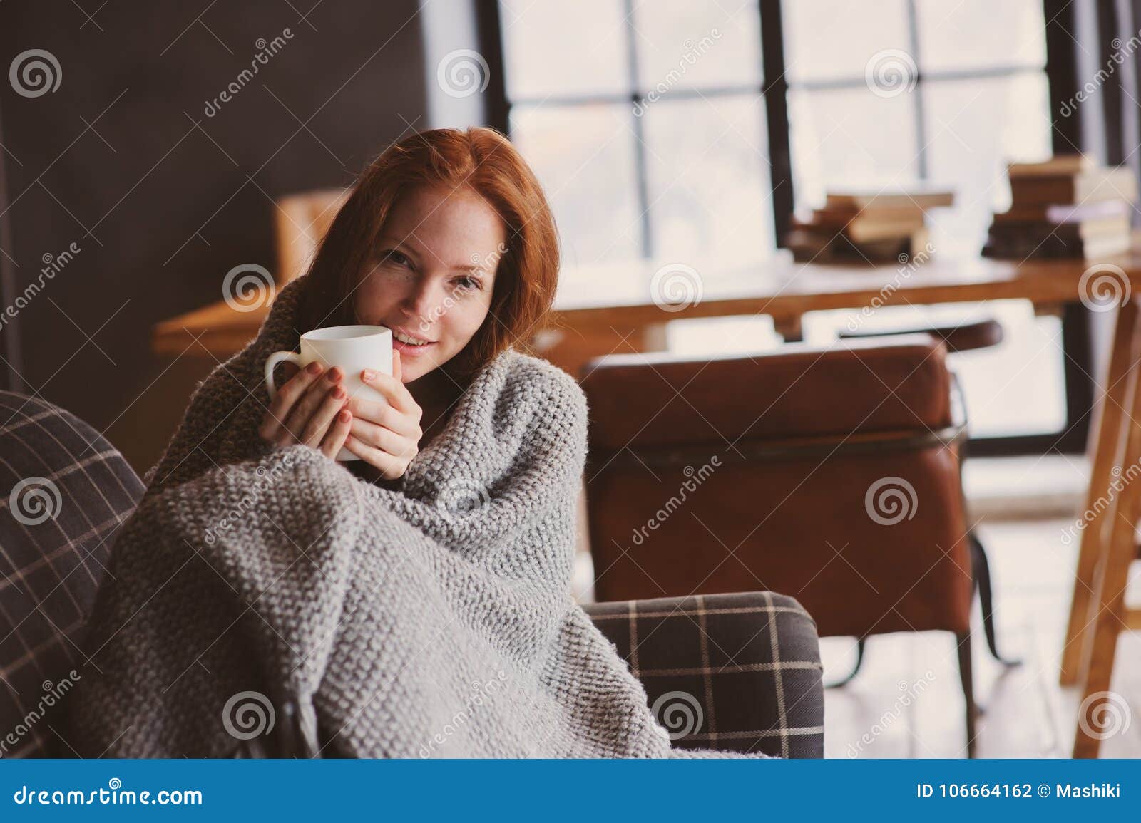 young sick woman healing with hot drink at home on cozy couch