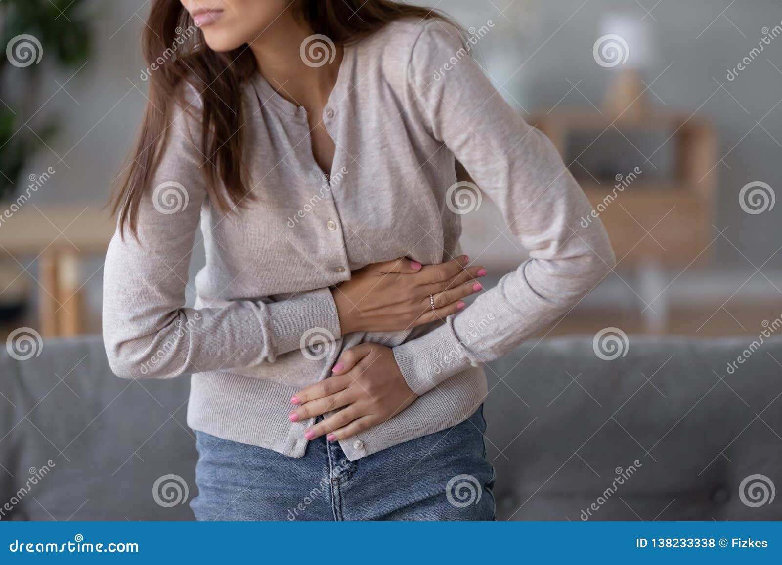 young sick woman standing holding belly suffering from stomach pain