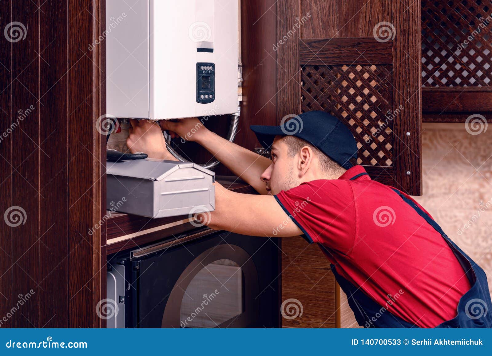 a young skilled worker regulates the gas boiler before use