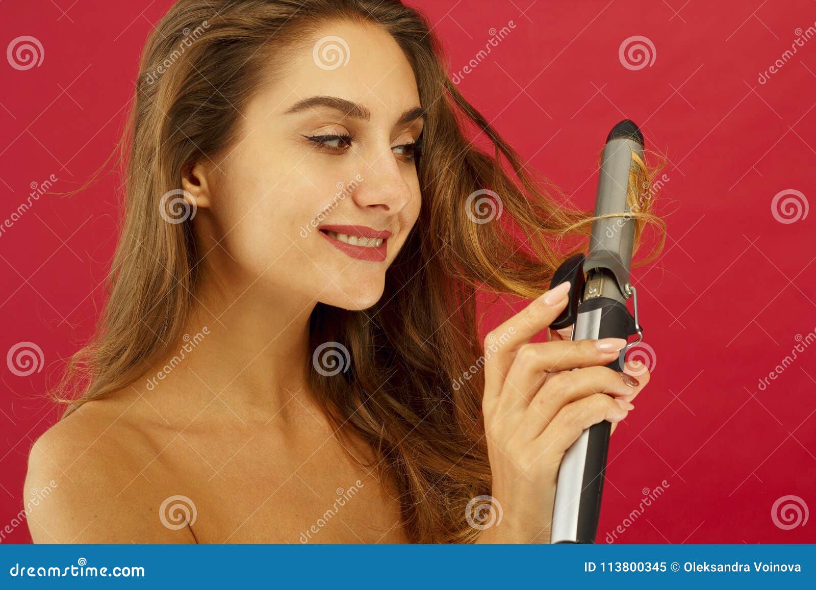 young smiley woman making curly hair by ploy over red background
