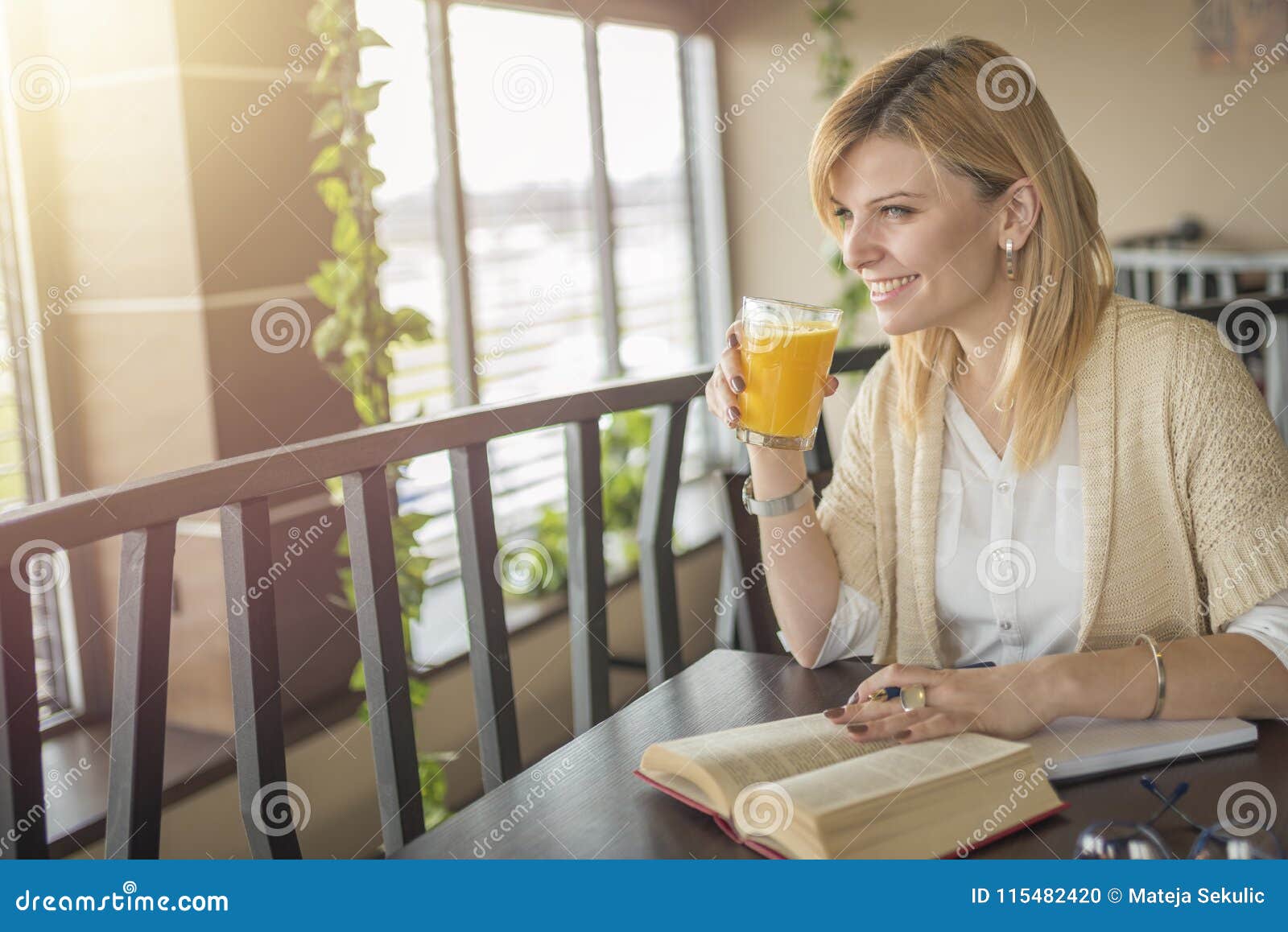 Young Smiling Blonde Woman in a Restaurant Reading a Book and Dr Stock ...