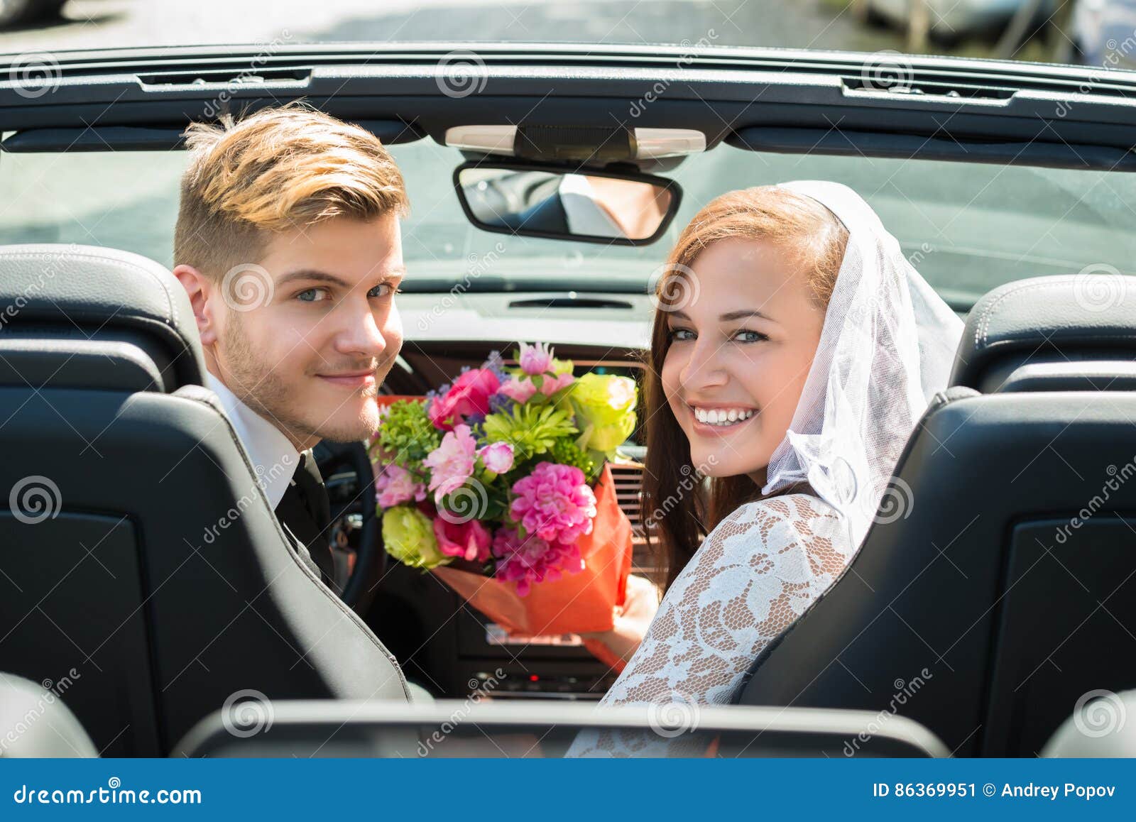 just married couple with bouquet in the car