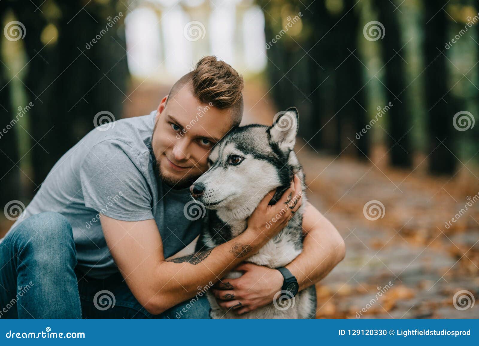 young smiling man hugging husky dog