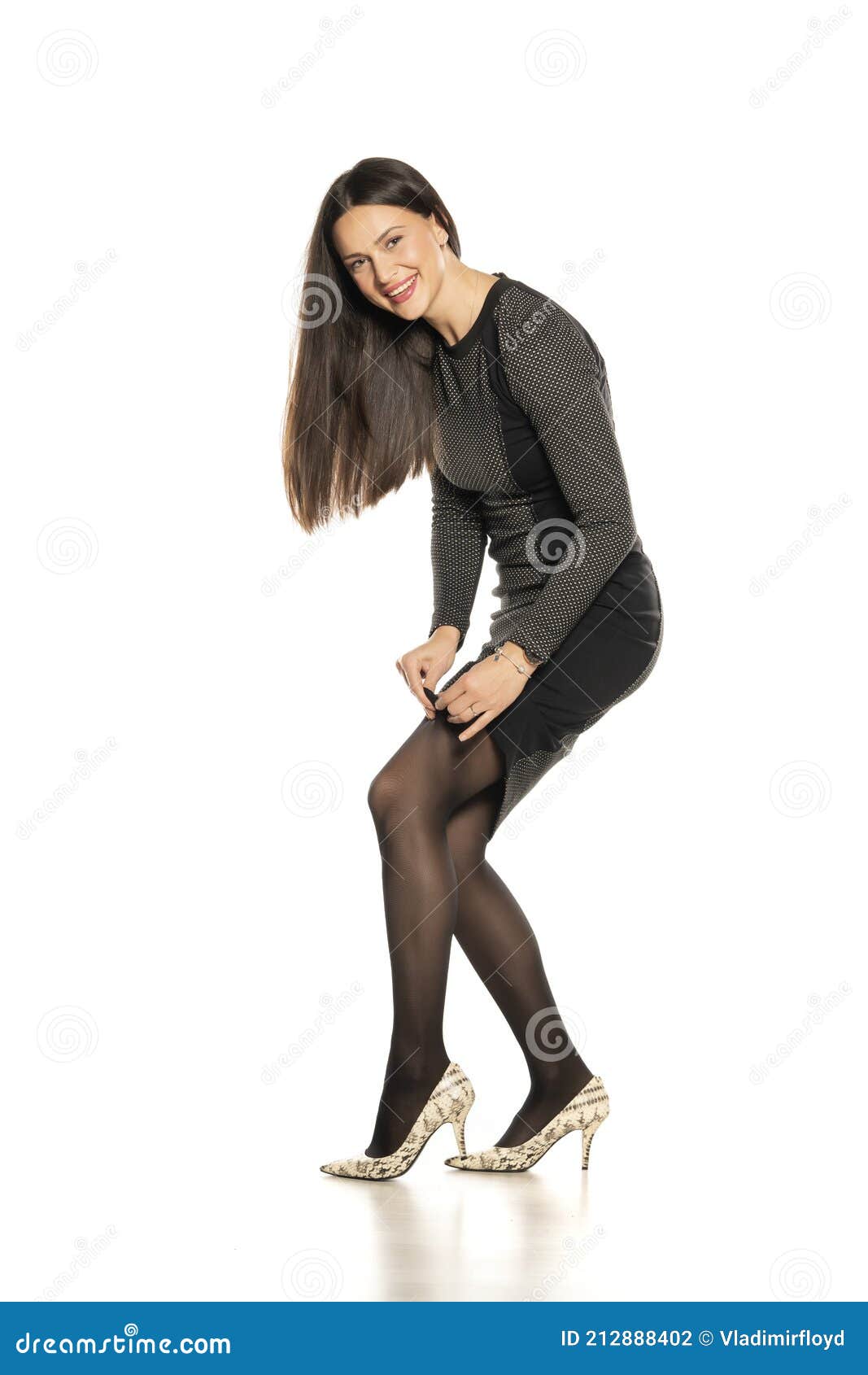 Young Smiling Woman in a Short Tight Dress Adjusting Her Leggings