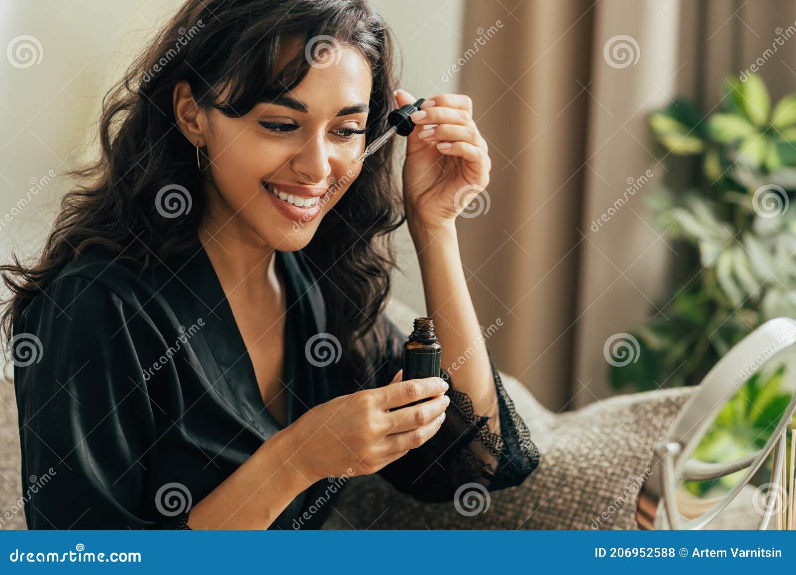 young smiling woman sitting on a couch applying hyaluronic acid on a face