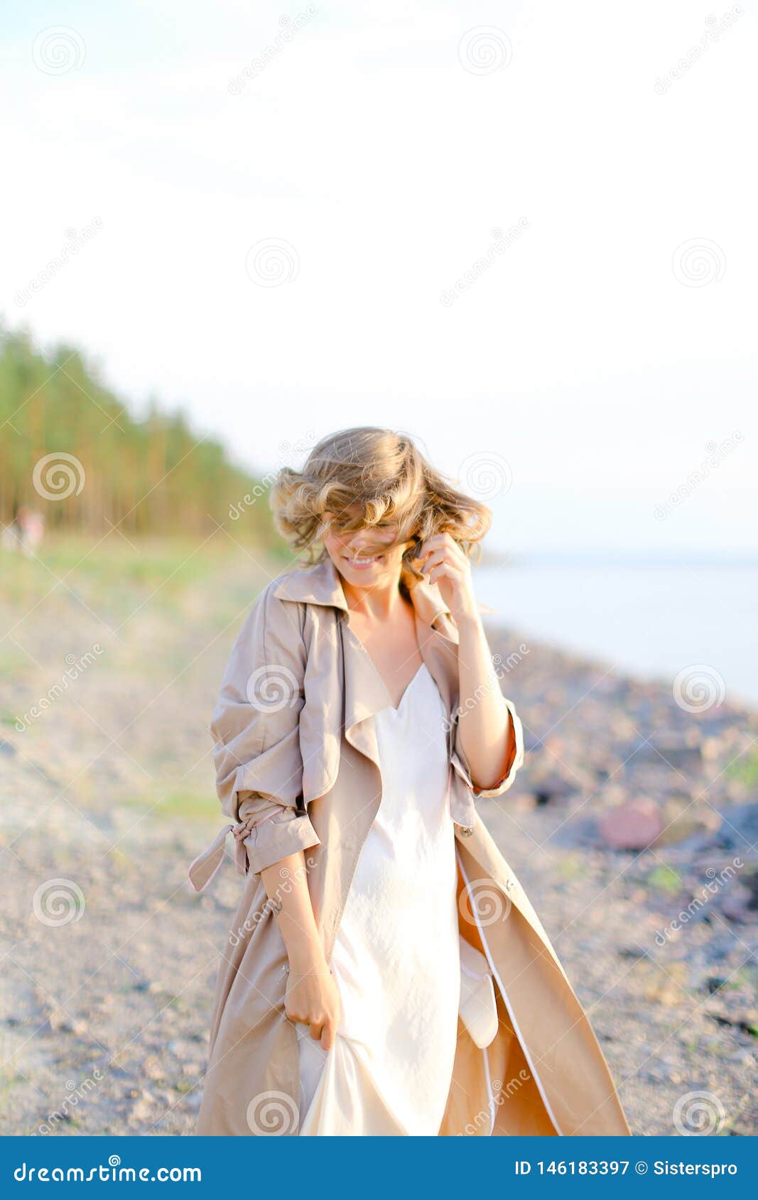 Young Smiling Woman Standing On Sea Beach And Wearing Coat With White