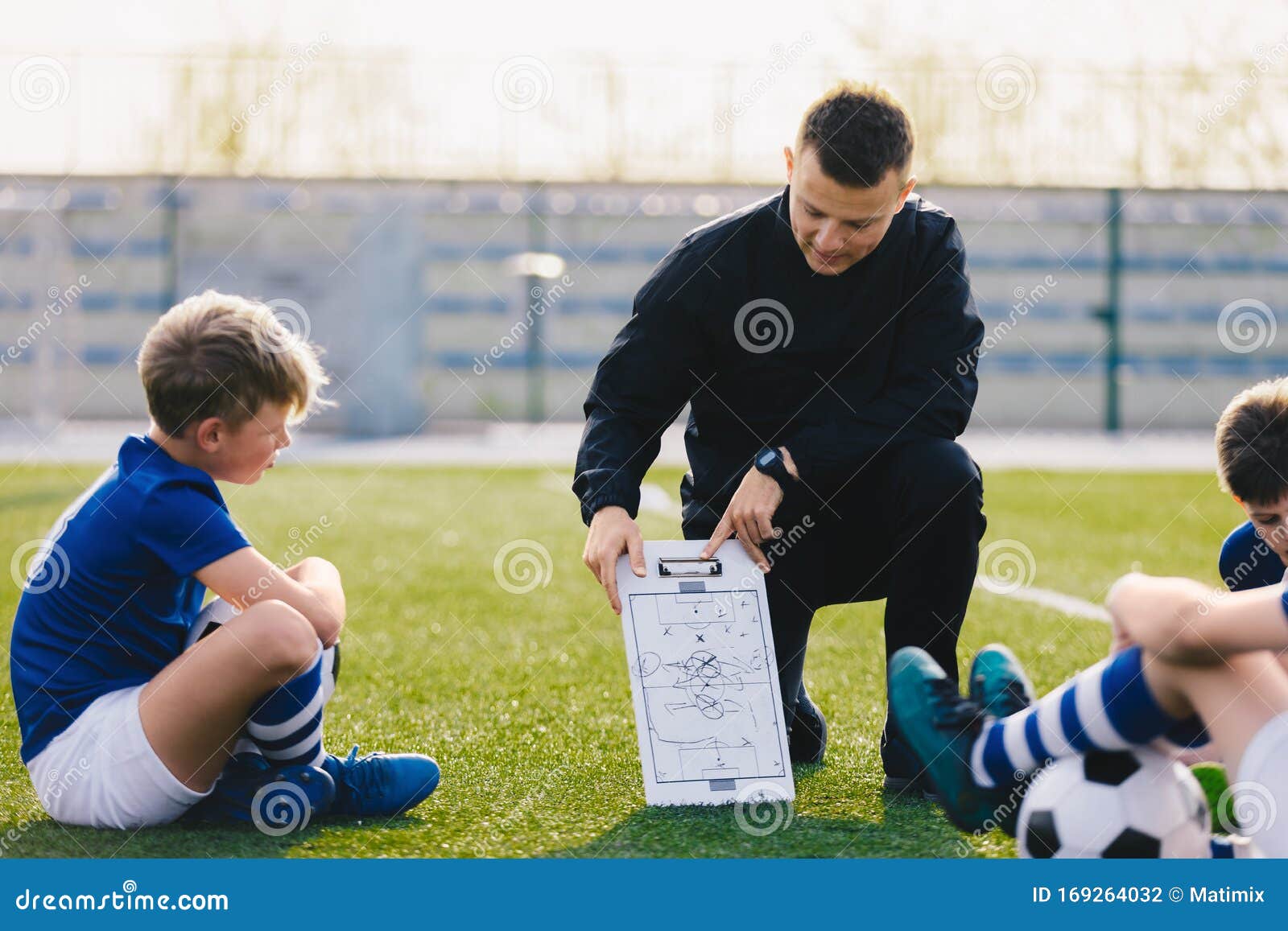 young soccer trainer coach explaining tactic on team sports tactics board